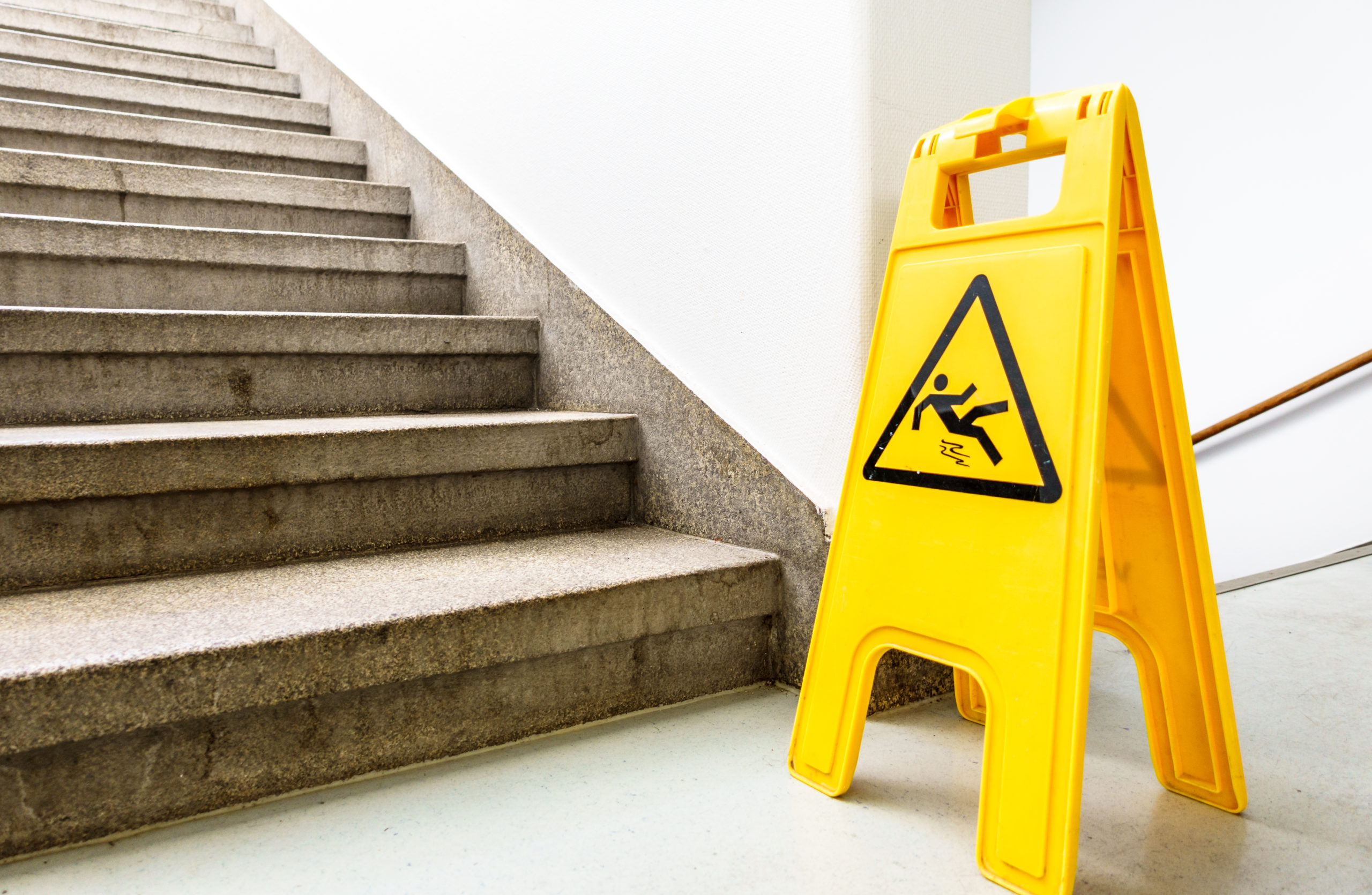 a wet floor warning sign in a stairwell, premises liability theme