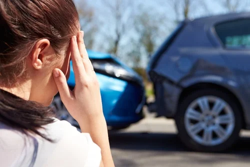 rear end car accident, woman holding her head in distress as the accident is partially her fault