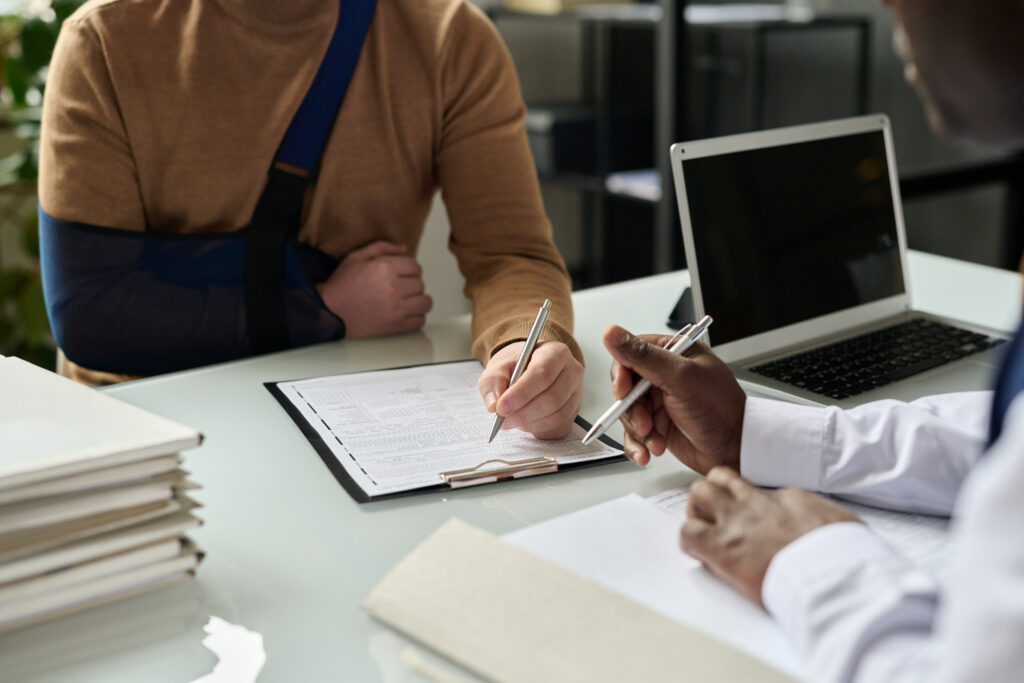 Personal Injury claim meeting with lawyer, Man signing form, injured man