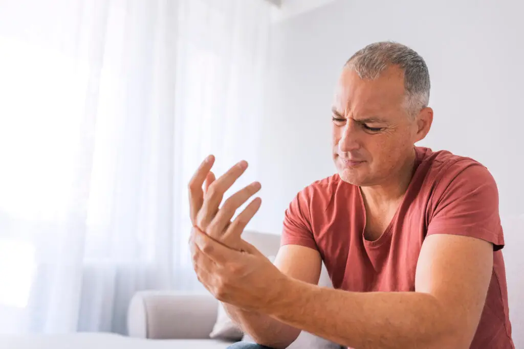 man sitting at a table holding his injured hand in pain after a personal injury accident