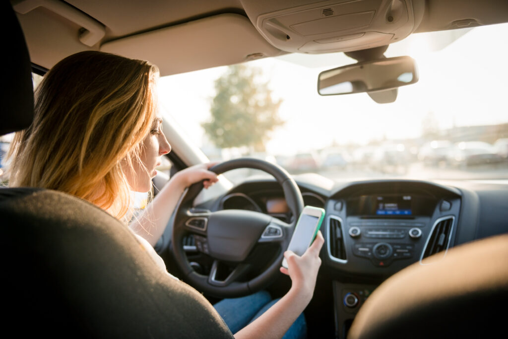 woman using a cell phone while driving, in danger of a car accident, distracted driving