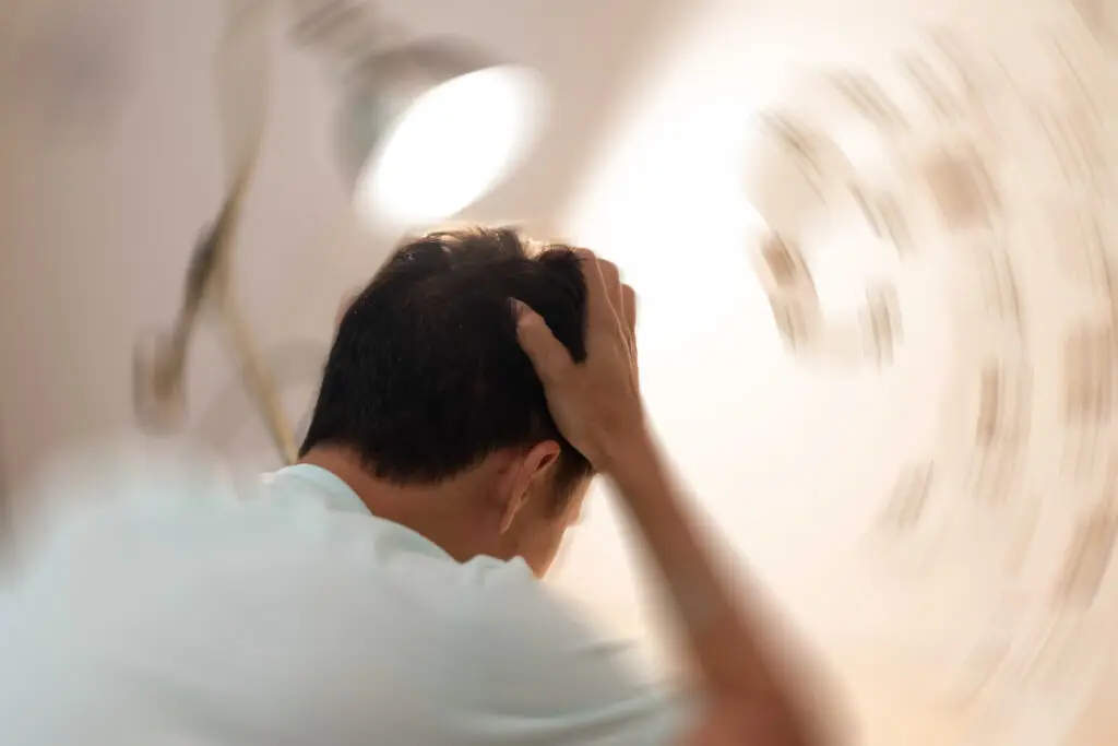 Vertigo illness concept. Man hands on his head felling headache dizzy sense of spinning dizziness,a problem with the inner ear, brain, or sensory nerve pathway due to a personal injury accident. Man holding his head while room is spinning