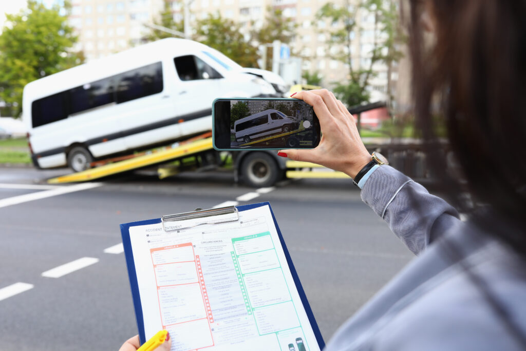 Woman insurance agent films broken minibus on smartphone. Comprehensive vehicle insurance concept