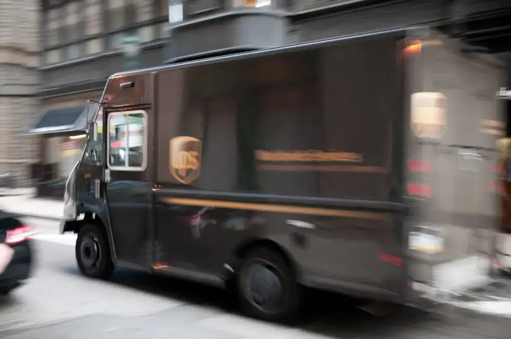 A UPS delivery truck travels down a narrow downtown street.