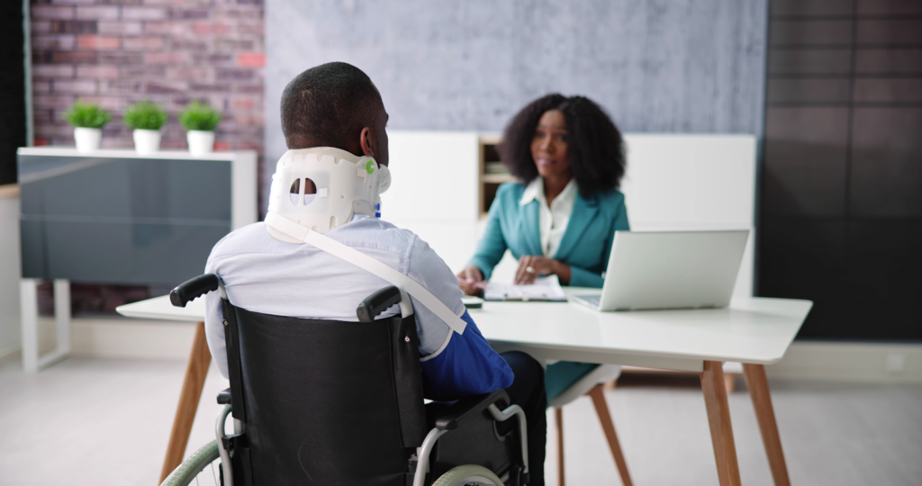 an accident injury victim in a wheelchair meeting with a personal injury lawyer to discuss out insurance claims