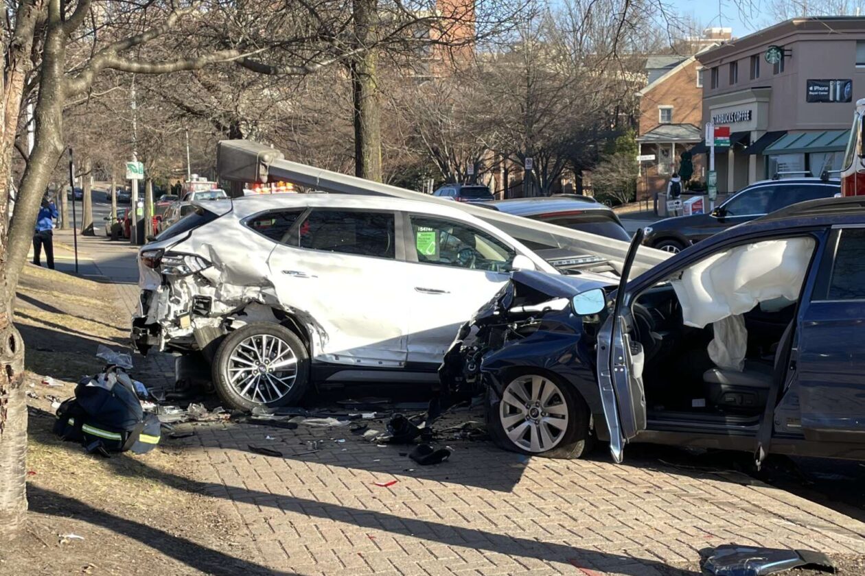 two cars sit damaged on a sidewalk after an accident in a residential neighborhood.