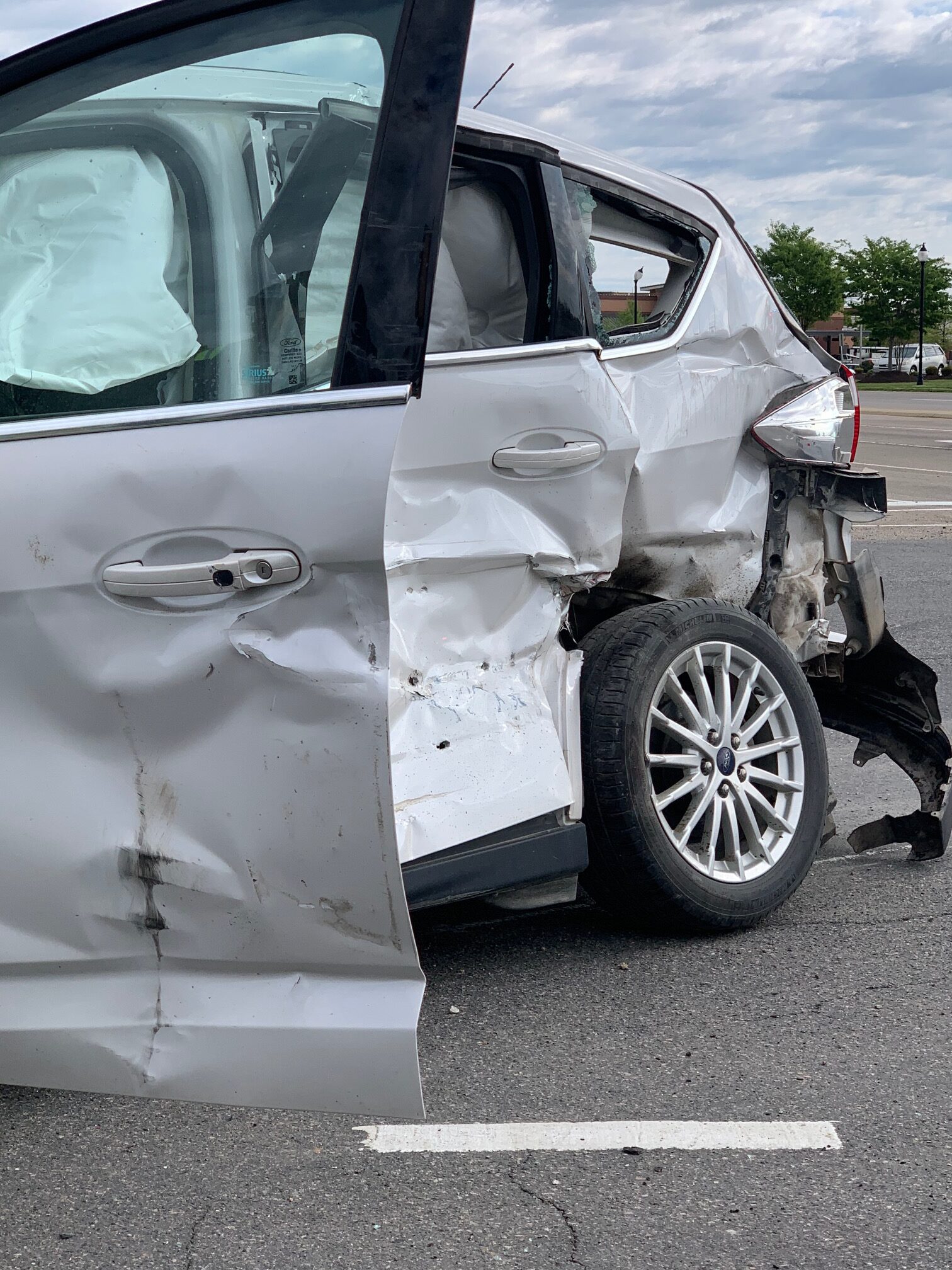 a silver car with heavy damage to its side panels after a high speed side impact collision.