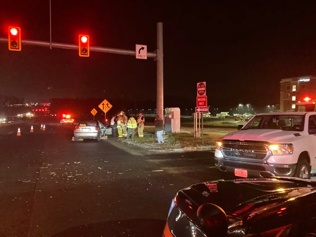 The aftermath of a car accident at an intersection in Richmond, VA, with an ambulance and other first responders tending to an injured passenger.
