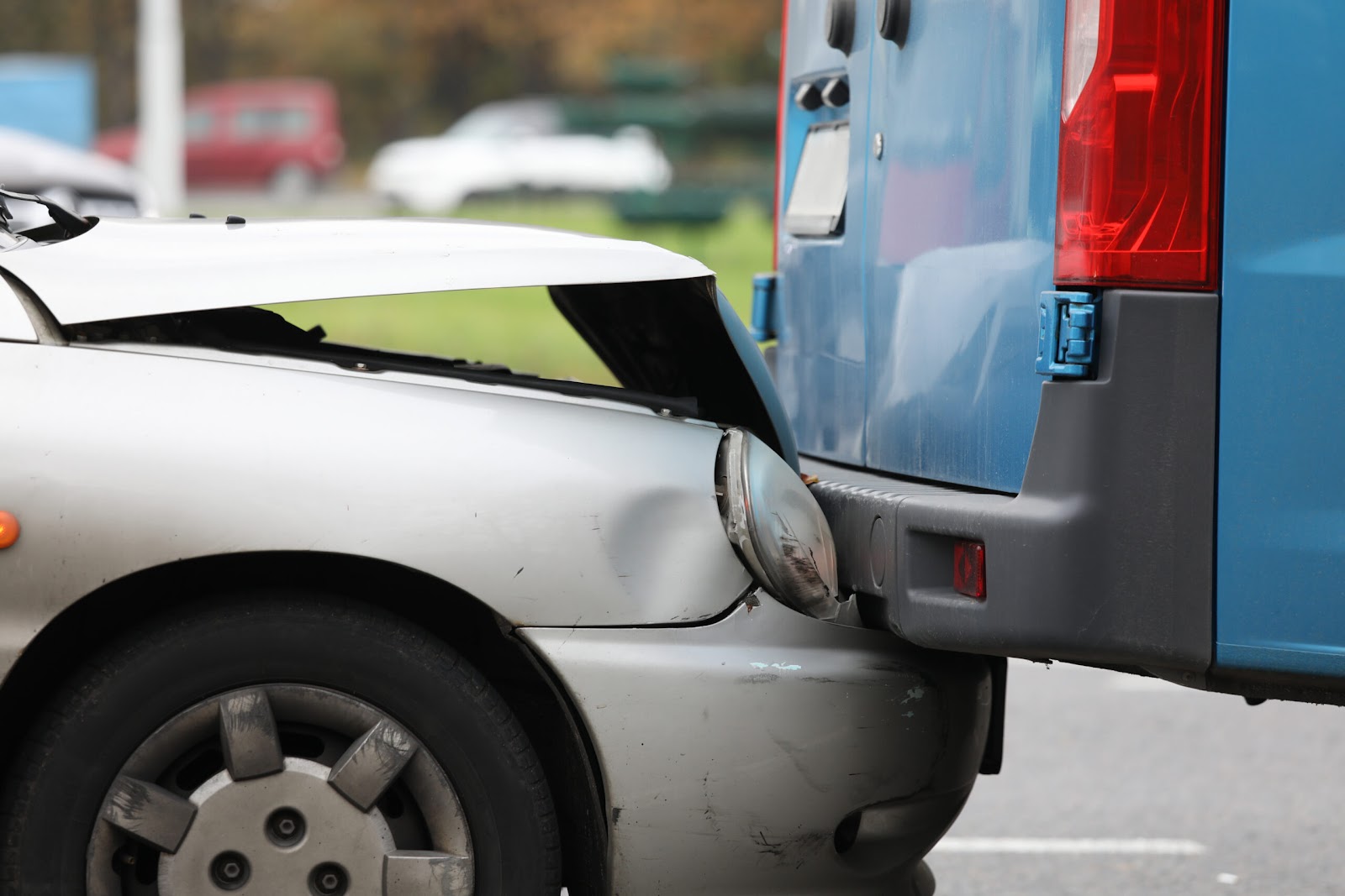 a silver car with front end damage after rear-ending a blue van