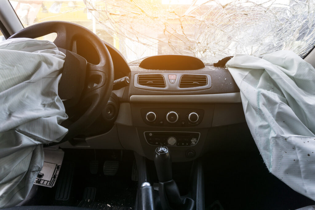 The inside of a car after a severe accident. The windshield is shattered, and the airbags are deployed.