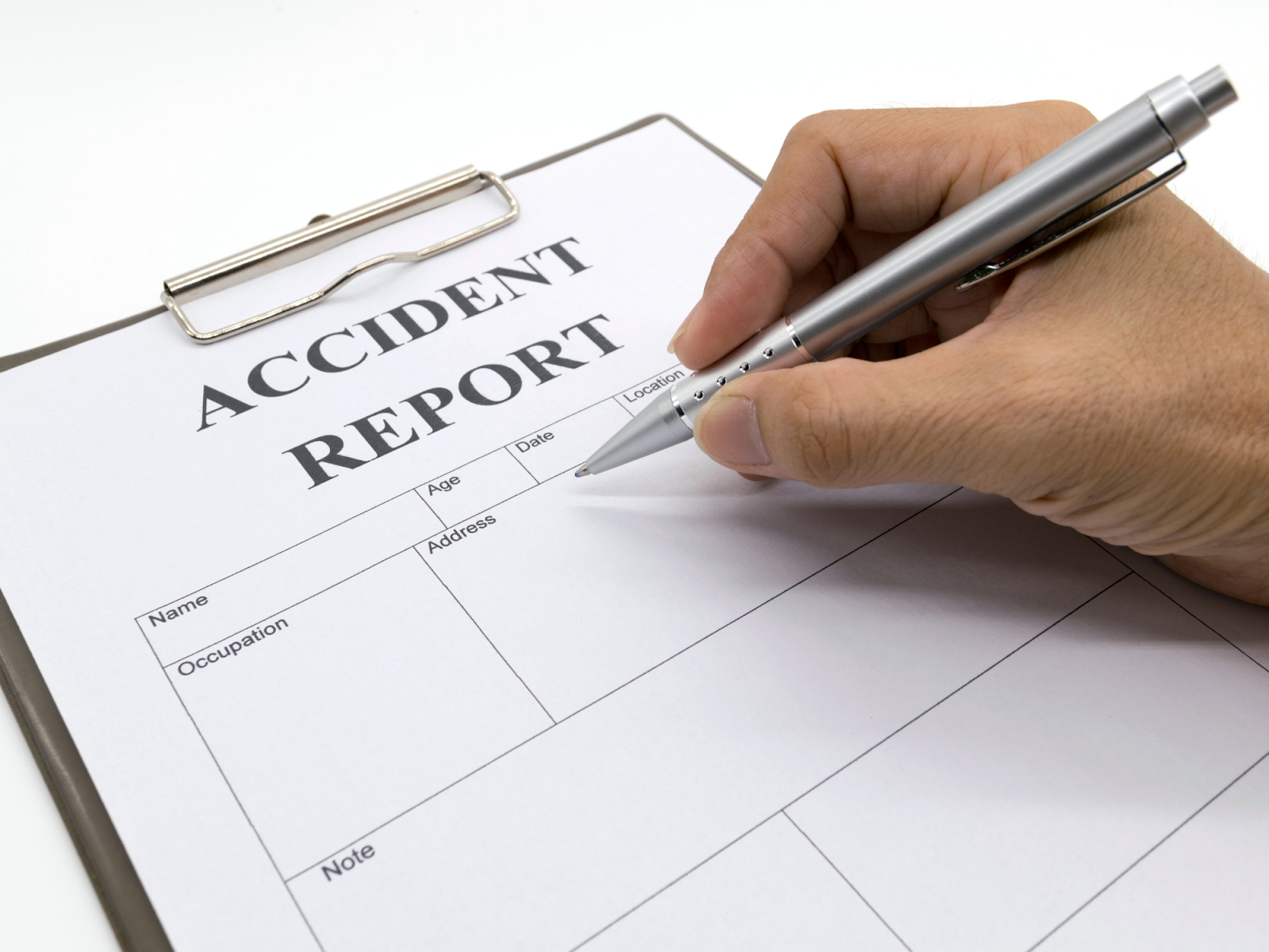 A close up view of someone filling out an accident report after a car accident.