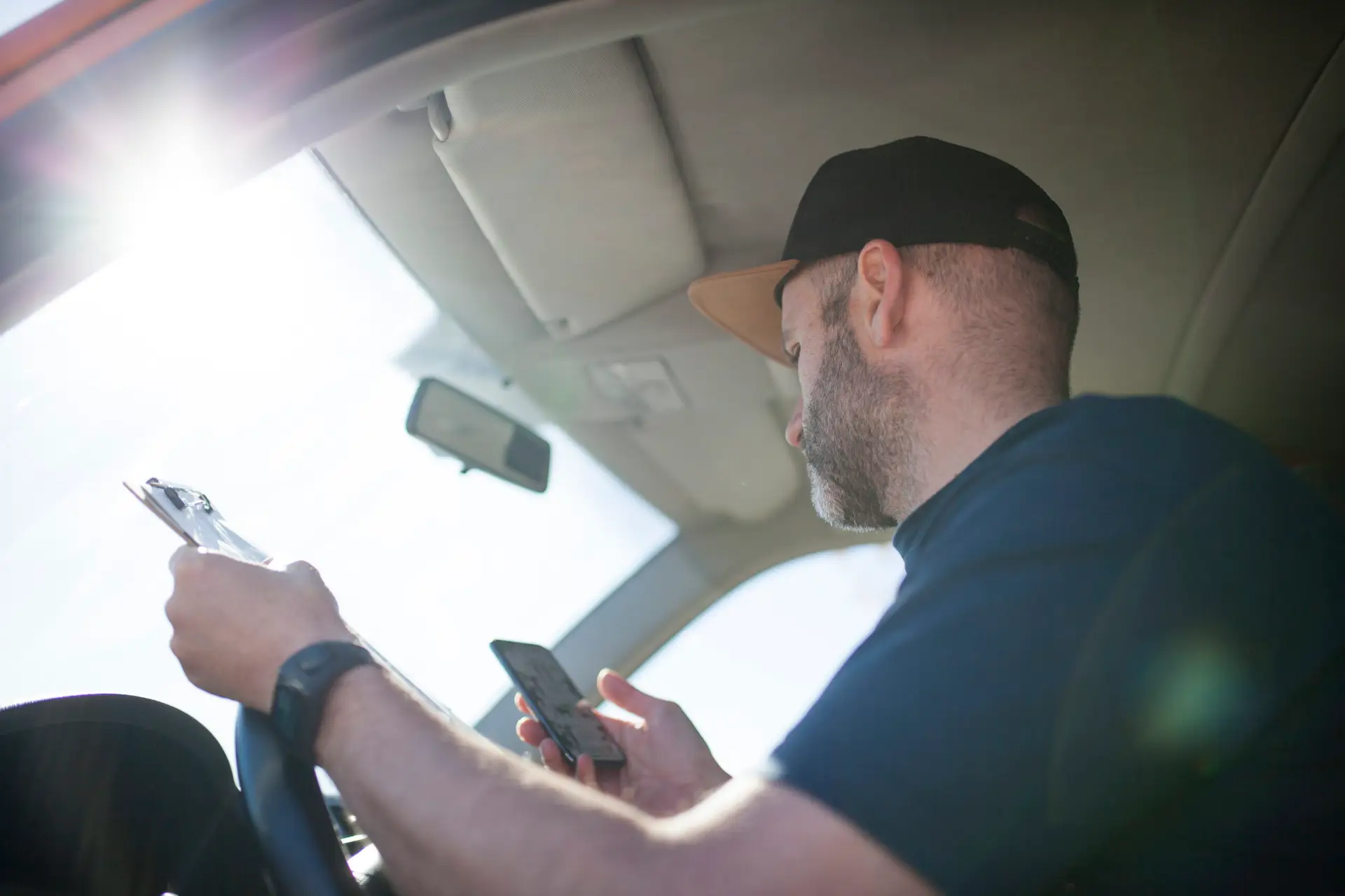a truck driver checks his phone for directions on his route, taking his eyes off of the road and creating the potential for an accident.