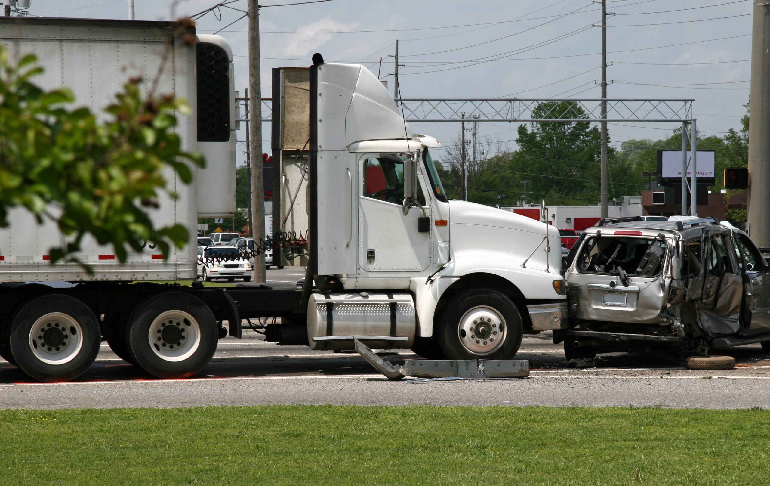 A semi collision with a minivan, causing massive damage to the minivan at an intersection.