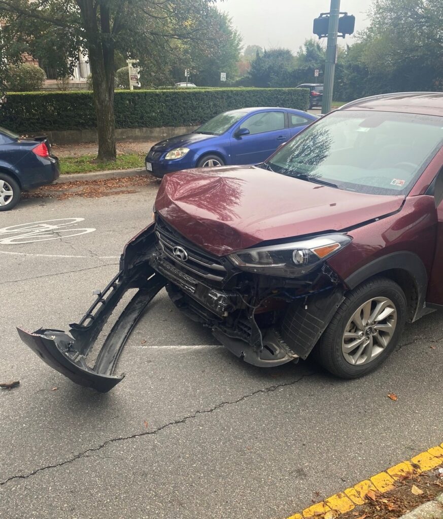 An SUV with a damaged front-end bumper and a dented hood after a car accident. 