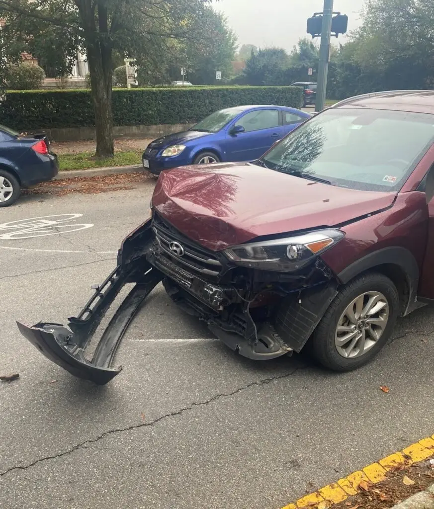 A maroon SUV with a detached front-end bumper after a head-on collision in Virginia.
