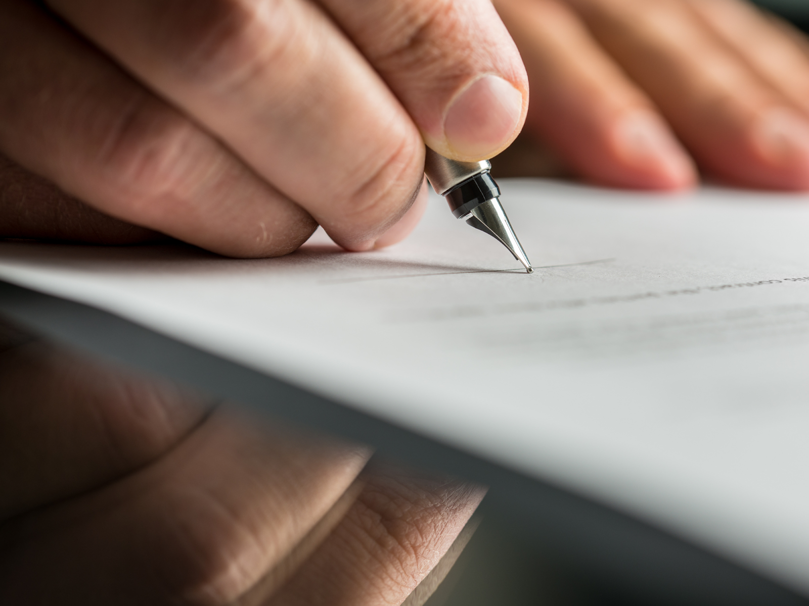 a woman's hand holding  a pen writing on a piece of paper