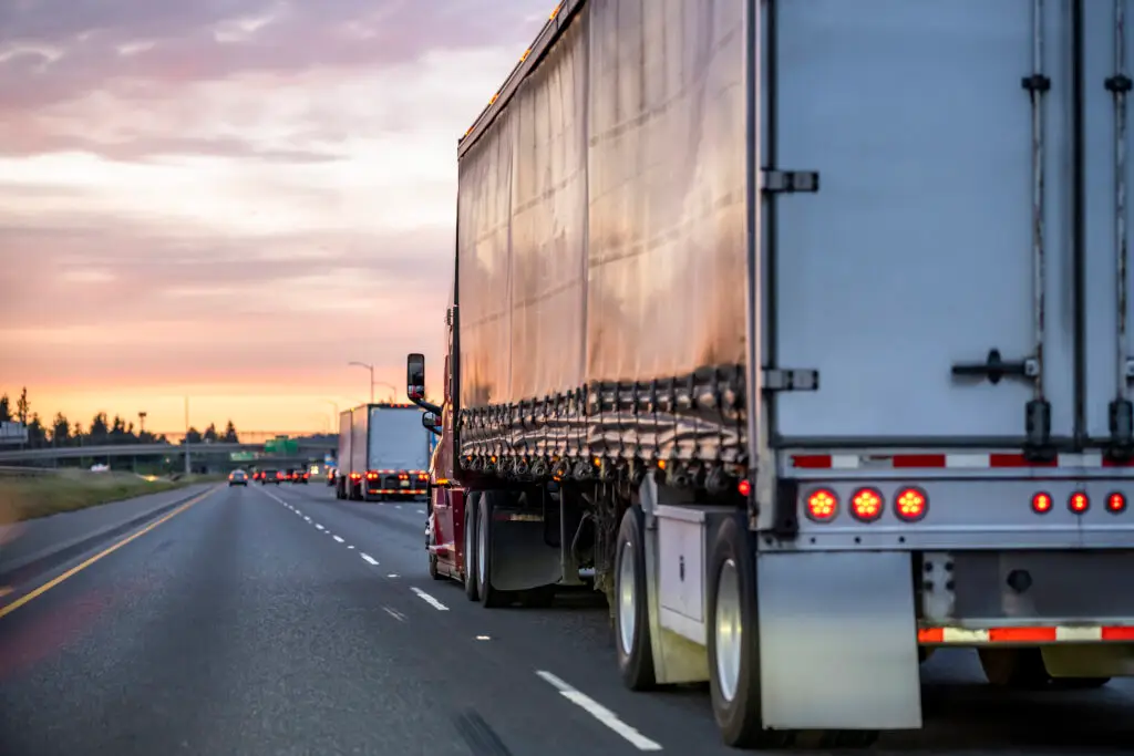 The view of a car driving alongside a semi-truck in its blind spot.
