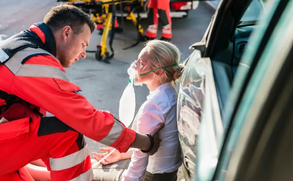 A first responder administers oxygen to a car accident victim.