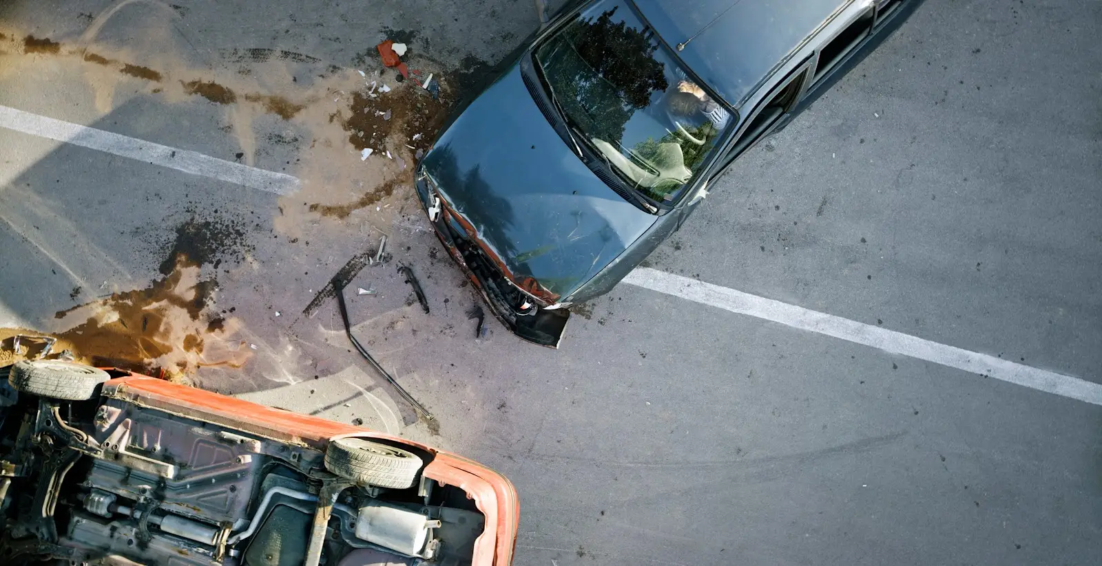 An aerial view of a car crash that resulted in one car being turned over and another car sustaining severe damage to the front end of the vehicle.