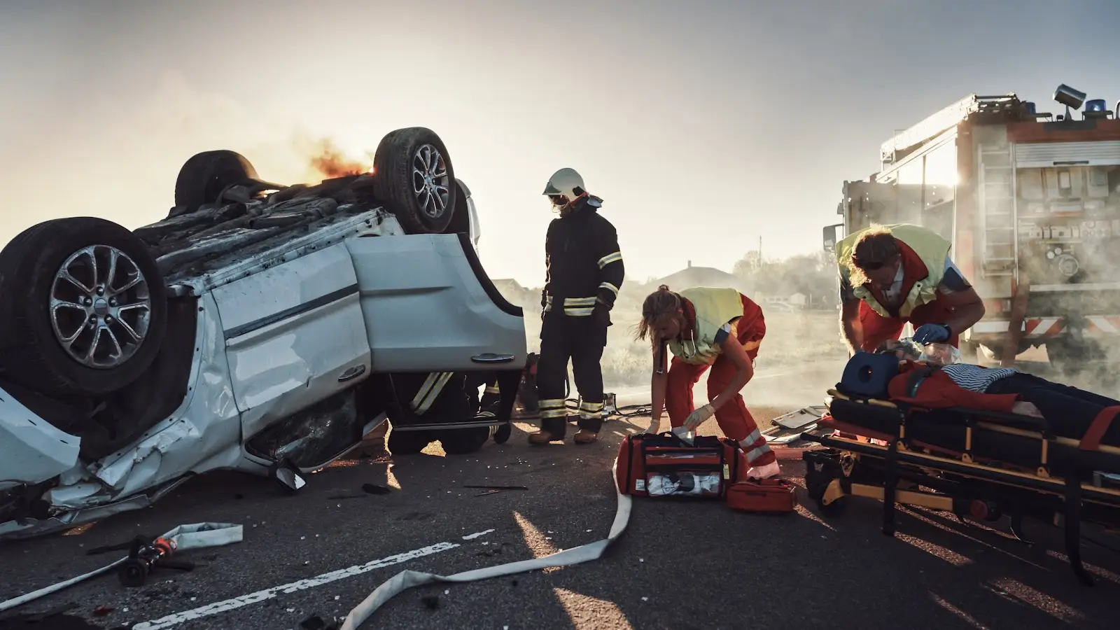 First responders at the scene of a fatal car crash give medical treatment to victims next to a white, overturned SUV