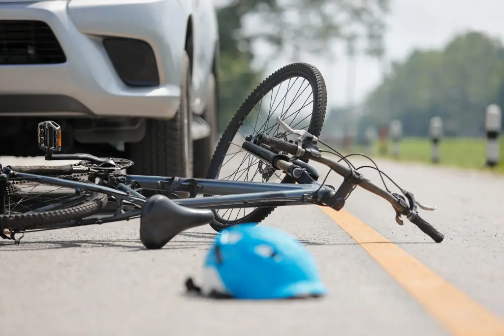bicycle on the ground in front of a car after an accident.