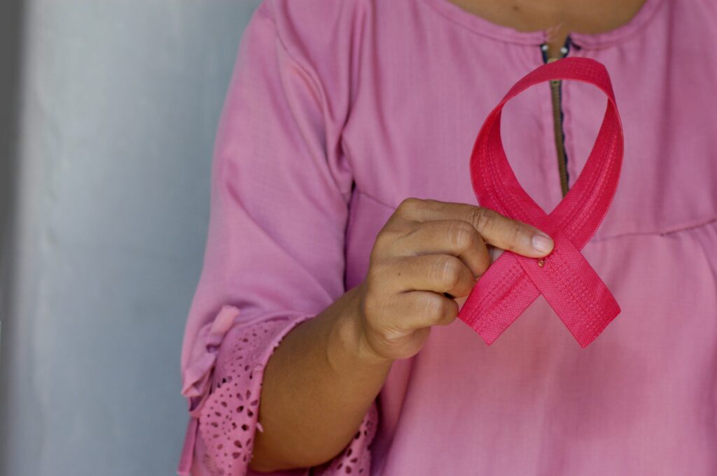 A woman holds a pink ribbon, a symbol of breast cancer awareness month, held every October.